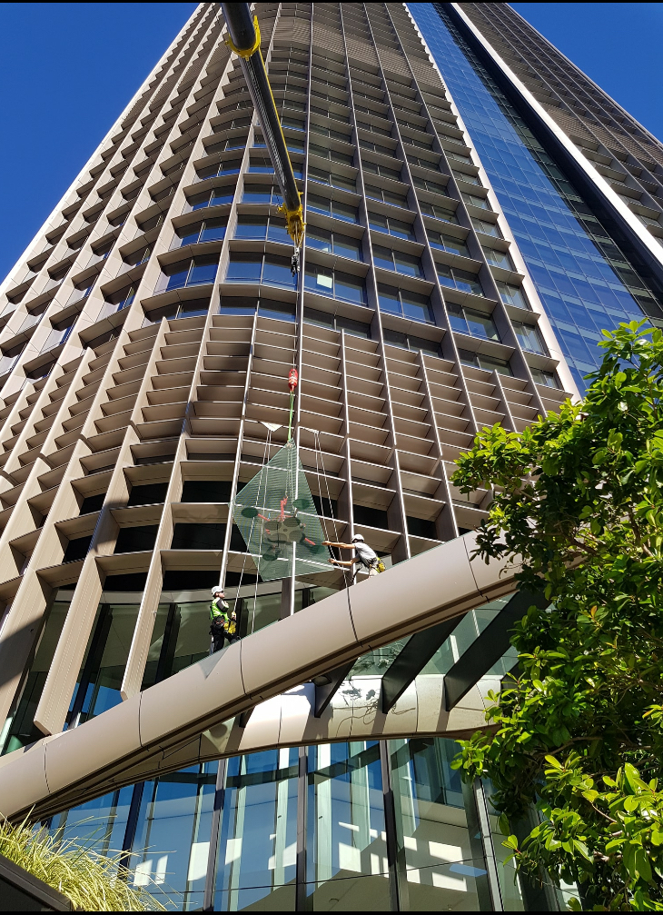Glass panel being lifted by crane up the bronze louvred façade of 1 William Street tower
