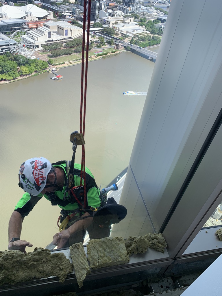 Rope access technician working at height with Brisbane River and South Bank in the background