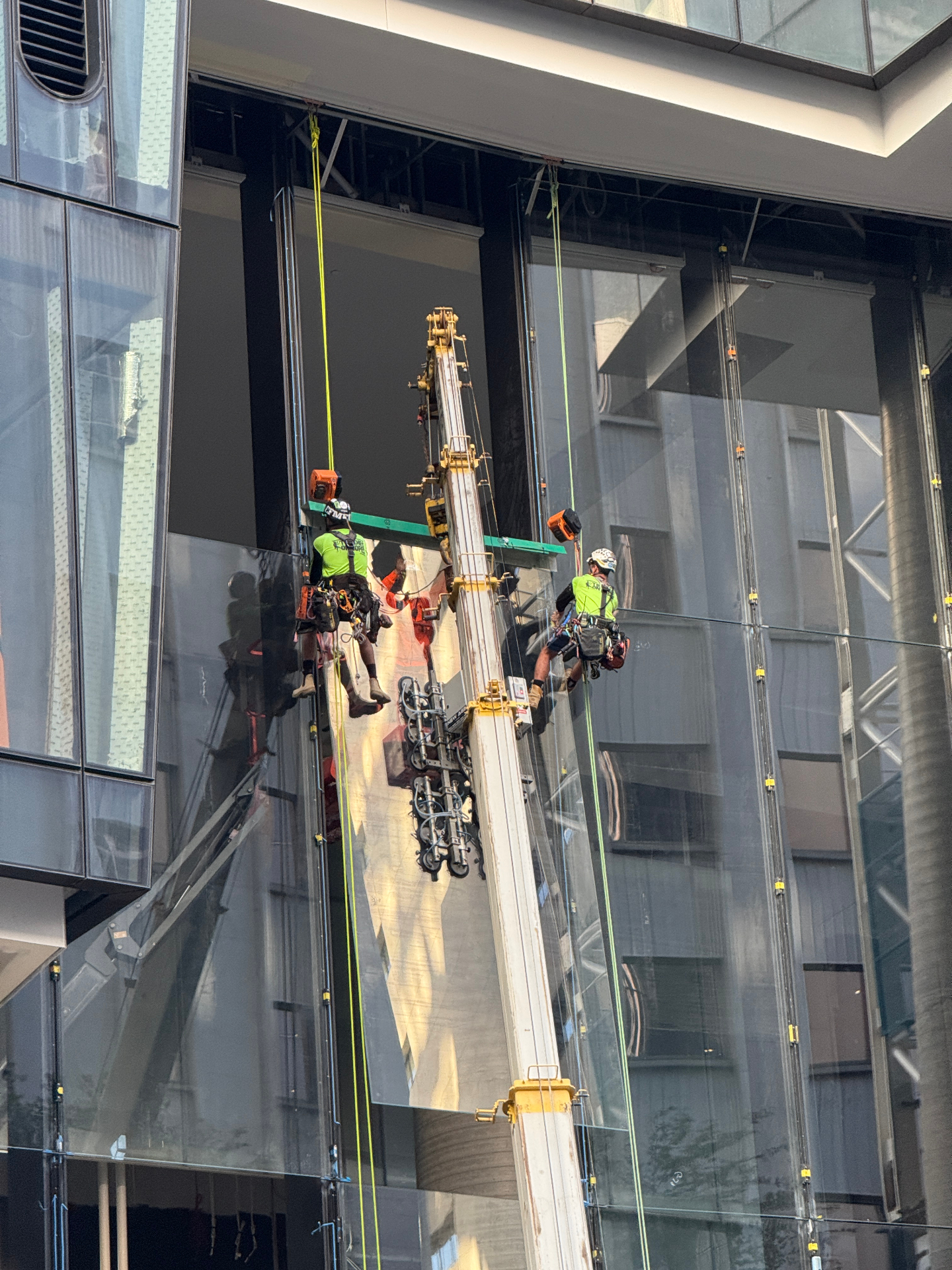 Two Tradies on Ropes technicians on ropes installing a large glass panel at 360 Queen Street