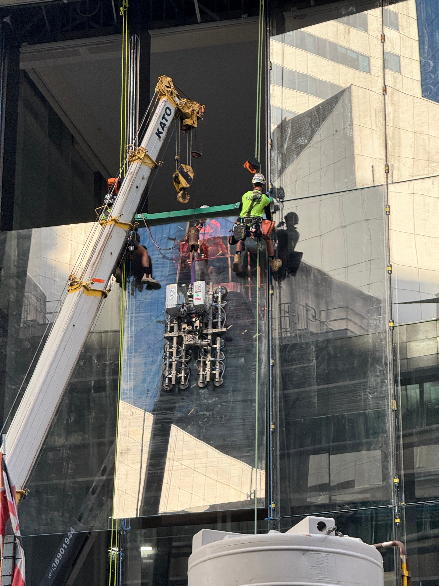 Rope access glazier guiding a Kato crane lift of a glass panel at 360 Queen Street Brisbane