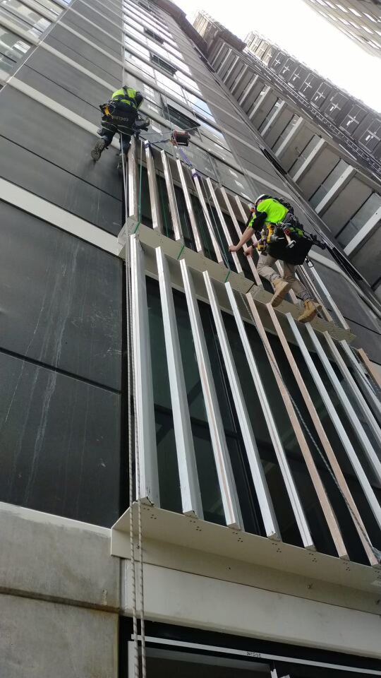 Rope access technician completing façade finishing works at Upper House South Brisbane