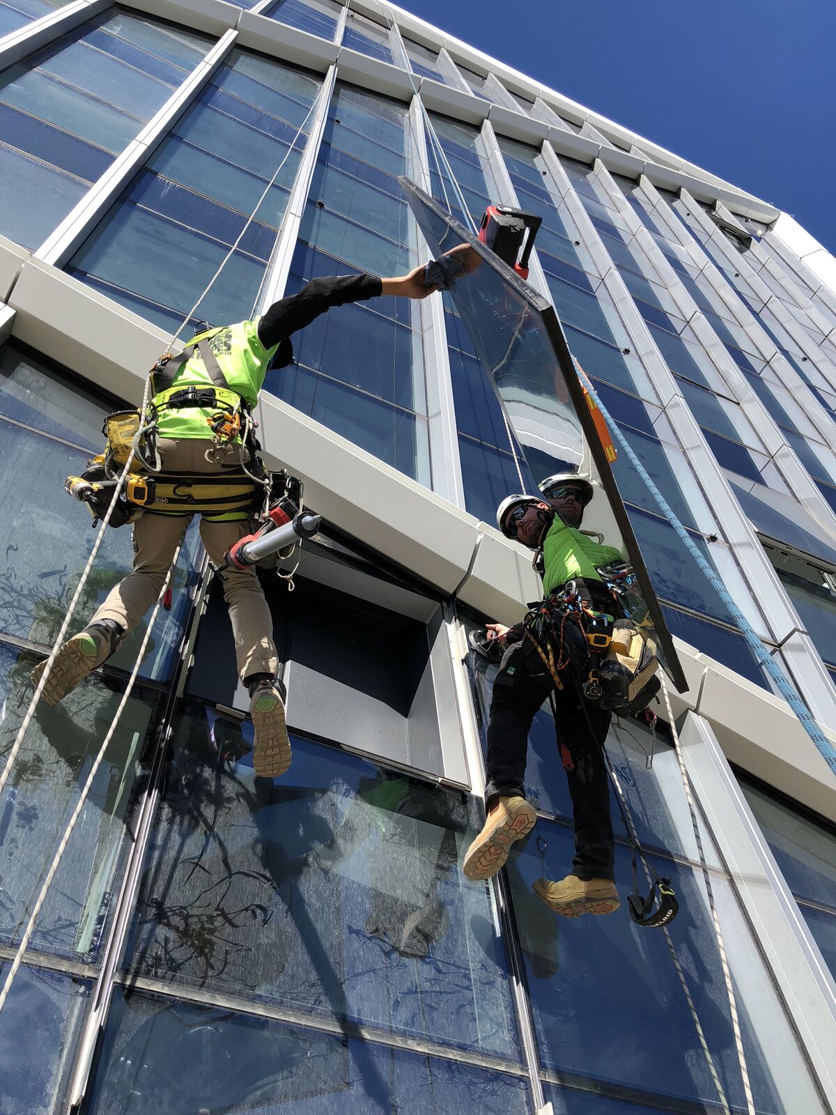 Two rope access technicians installing angled glazing panel at Jewel Gold Coast
