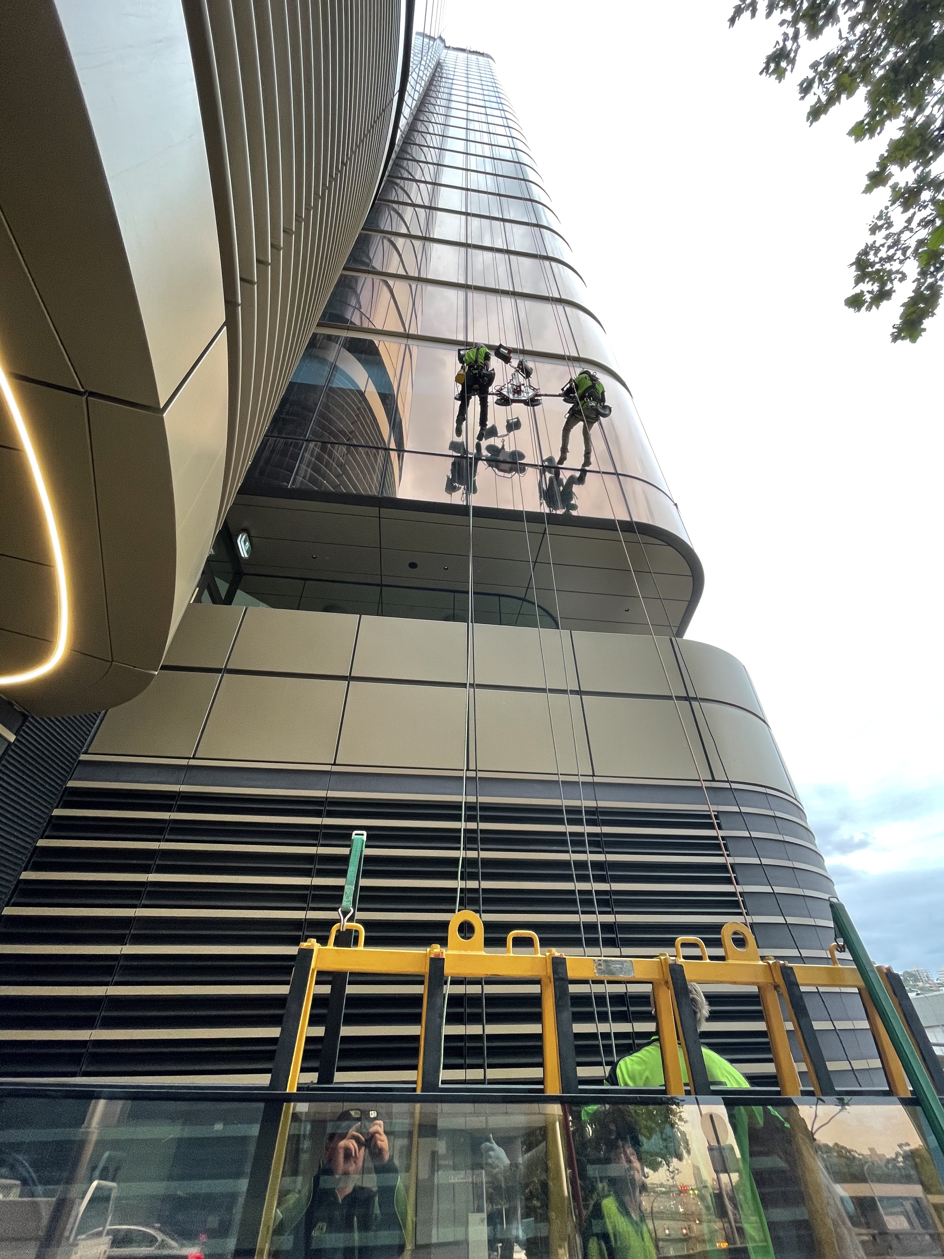 Two rope access technicians working on the curved glazed façade of Zurich Tower at 118 Mount Street North Sydney