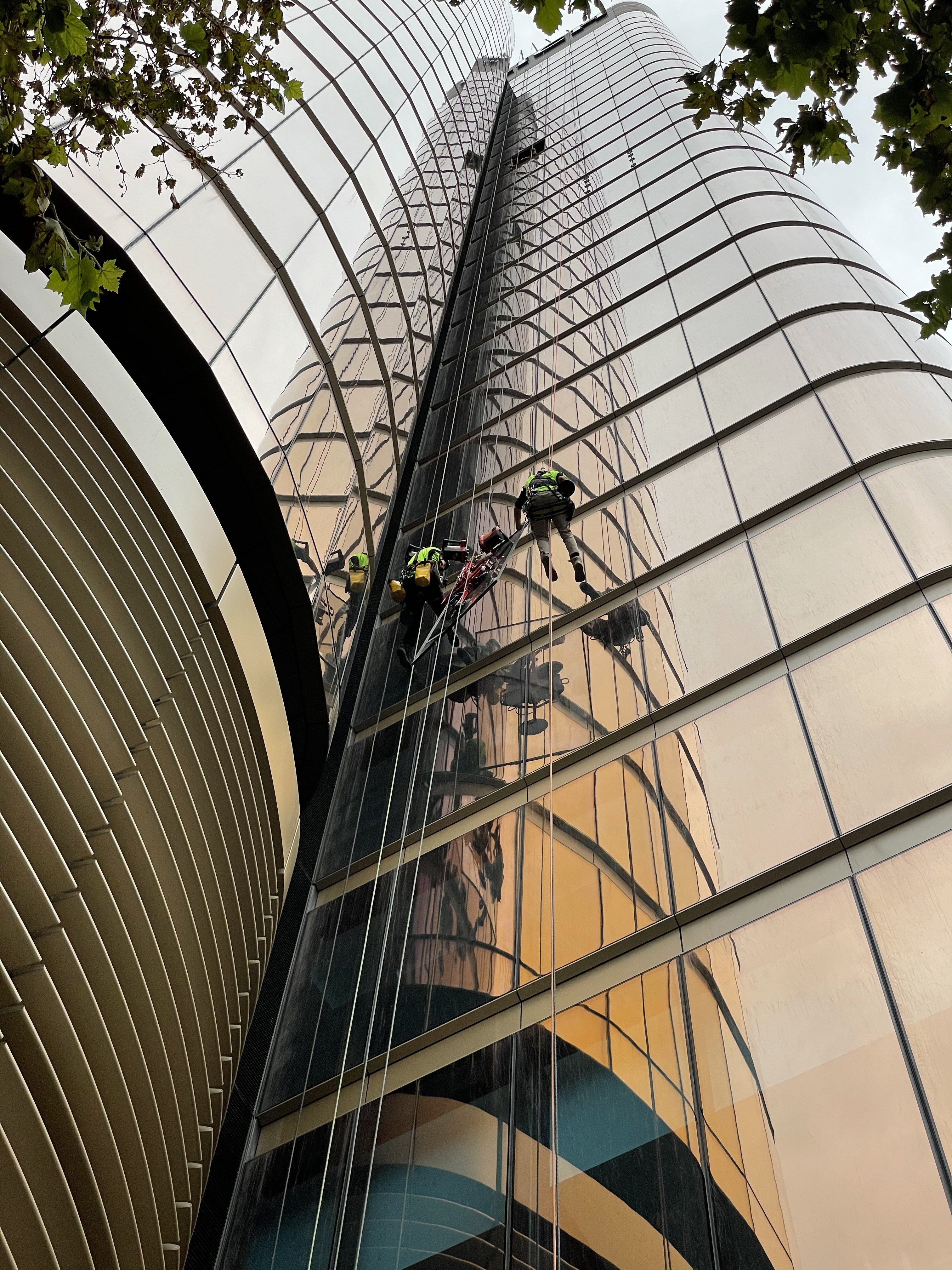 Close-up of rope access façade works on Zurich Tower with reflected curved glass panels